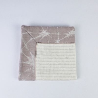 Guardanapo de algodão com padrão tie-dye cinza e branco e recorte listrado branco.