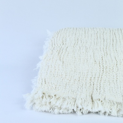 Tapete branco felpudo com franjas sobre superfície branca