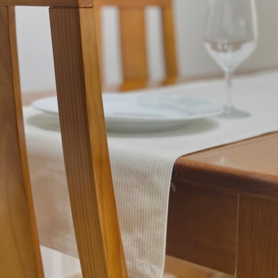 Mesa de jantar em madeira clara com toalha branca, prato e copo