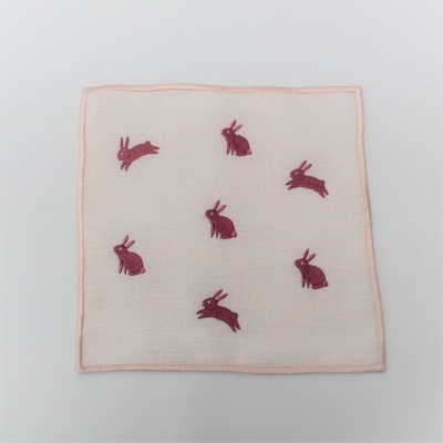 Lenço branco com bordas cor-de-rosa e coelhos bordados em rosa.