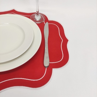 Conjunto de pratos brancos, faca metálica, copa e sousplat vermelho com bordas brancas