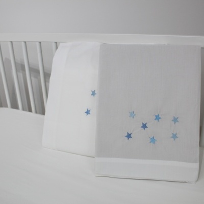 Duas fraldas brancas com estrelas azuis sobre um berço branco