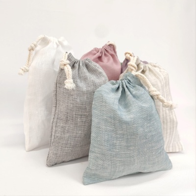 Cinco sacos de tecido coloridos com fecho em cordão sobre fundo branco