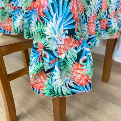 Toalha de mesa com padrão tropical colorido sobre mesa de madeira