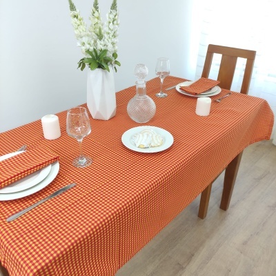 Toalha de mesa vermelha e amarela com acessórios de jantar e decoração
