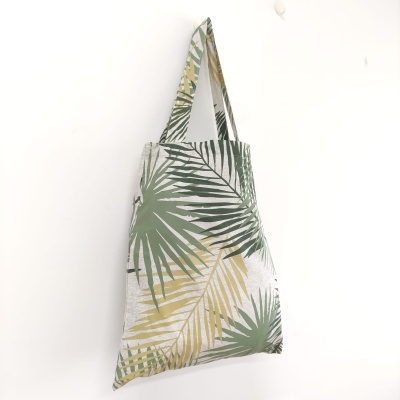 Saco de tecido verde e amarelo com padrão de folhas pendurado