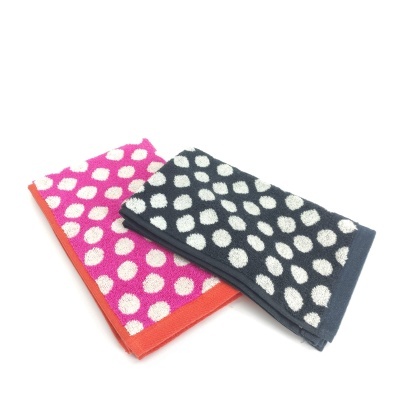 Duas toalhas de mão em algodão com padrão de bolinhas brancas, uma rosa e outra cinzento escuro.