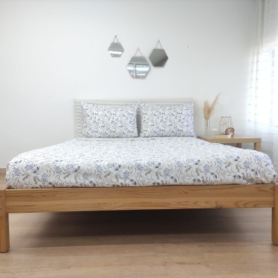 Cama de madeira clara com roupa de cama floral e espelhos geométricos na parede