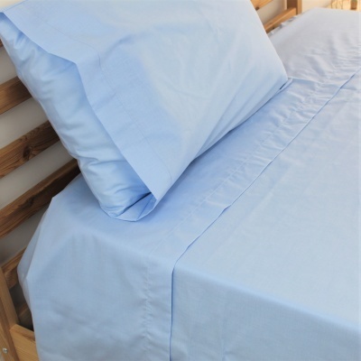 Lençóis azuis claros em cama de madeira clara