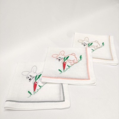 Três toalhas brancas com bordado de coelho e cenoura em diferentes cores nas bordas