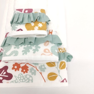 Conjunto de três toalhas brancas com padrões florais coloridos e folhos verdes