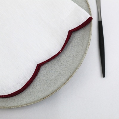 Guardanapo branco com borda castanha em prato cinzento com garfo preto