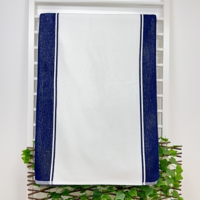 Toalha branca com faixas azul-escuras pendurada numa estrutura branca com folhas verdes