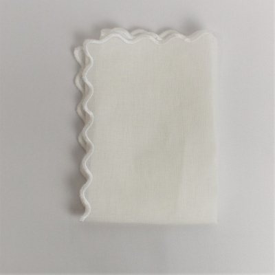Guardanapo branco com borda ondulada sobre superfície branca