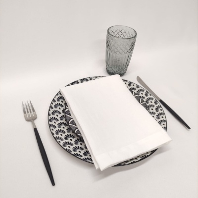 Conjunto de prato, guardanapo, talheres e copo sobre mesa branca