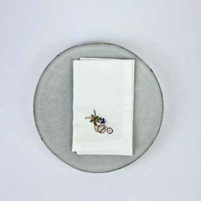 Guardanapo branco bordado com bicicleta e flores sobre prato cinza