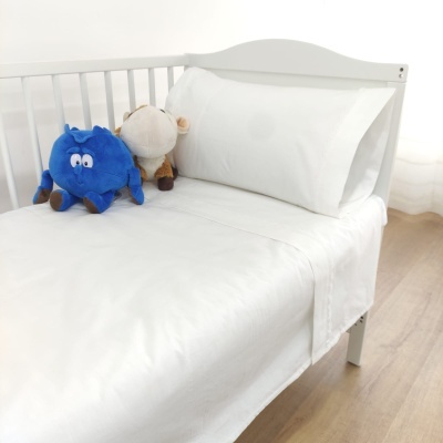 Cama de bebé com roupa branca e dois peluches coloridos