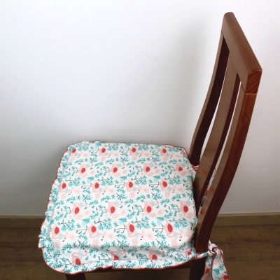 Capa almofadada para assento de cadeira com padrão floral cor-de-rosa e verde.