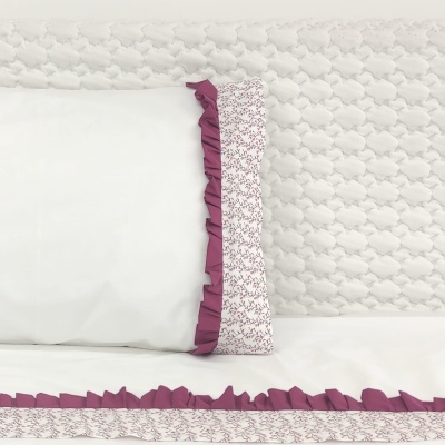 Travesseiro e lençol com franjas roxas e bordado floral em fundo branco