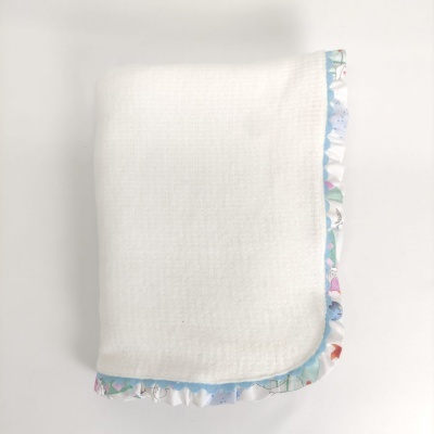 Toalha ou manta branca com borda azul e babados coloridos