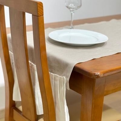 Mesa de madeira com toalha bege, prato branco e copo de vidro