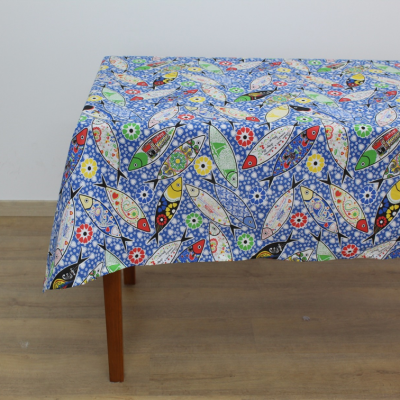 Toalha de mesa azul com padrão de peixes e flores coloridas sobre mesa de madeira