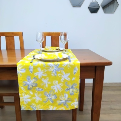 Toalha de mesa amarela com padrão floral sobre mesa de madeira e decoração interior