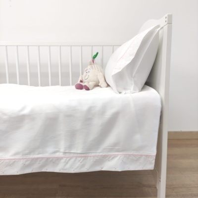 Berço branco com roupas de cama brancas e boneco de pelúcia