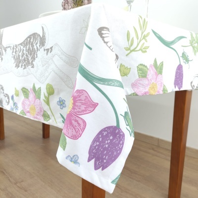 Toalha de mesa branca com estampa colorida de flores e gato sobre mesa de madeira