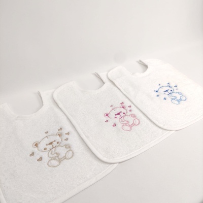 Três babetes brancos com ursinhos bordados em castanho, rosa e azul