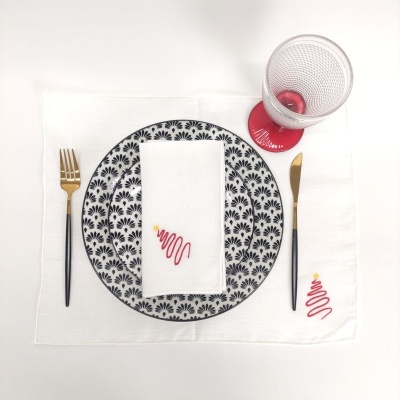 Conjunto de prato, guardanapo, toalhete, talheres e copo numa mesa branca