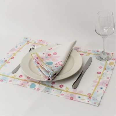 Conjunto de mesa com individual e guardanapo florais, prato branco, talheres de metal e copo de vidro