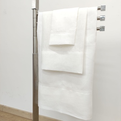 Três toalhas brancas penduradas em suporte metálico