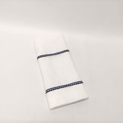 Toalha branca com detalhes azuis dobra sobre superfície branca