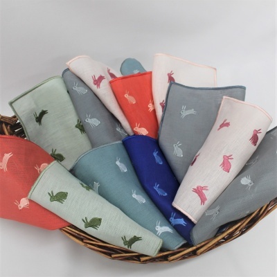 Panos de tecido coloridos bordados com coelhos em cesto de verga