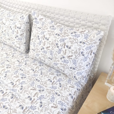 Conjunto de cama com estampado floral azul e cinza e cabeceira branca almofadada