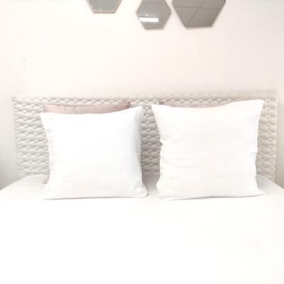 Cama com cabeceira acolchoada cinzenta e almofadas brancas e rosa