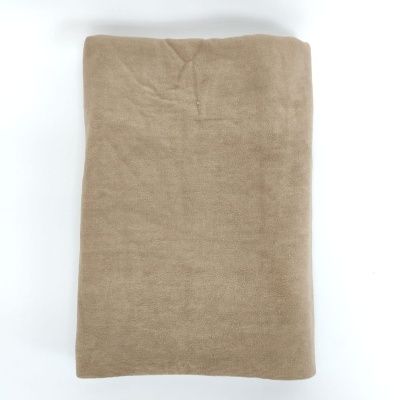 Cobertor bege dobrado sobre fundo branco