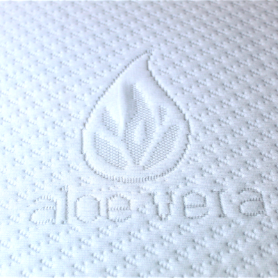 Superfície branca texturada com bordado em relevo de chama, folha e texto aloe vera