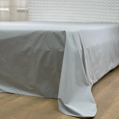 Lençol branco ajustado numa cama com cabeceira branca texturizada