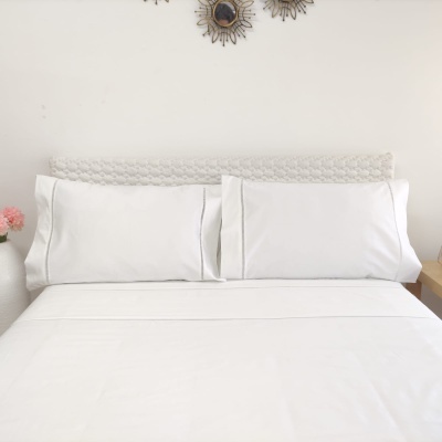 Conjunto de roupa de cama branca com lençol e fronhas em cama com fundo decorativo