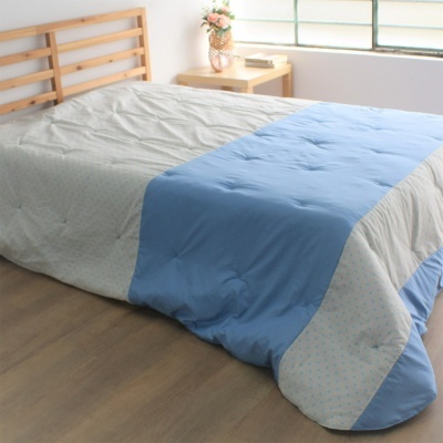 Edredão azul claro e cinza numa cama de madeira em quarto com mesa de cabeceira e vaso de flores