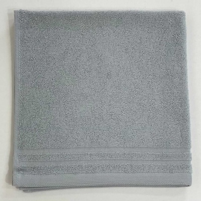 Toalha de banho cinzenta dobrada com textura felpuda e linhas horizontais na borda