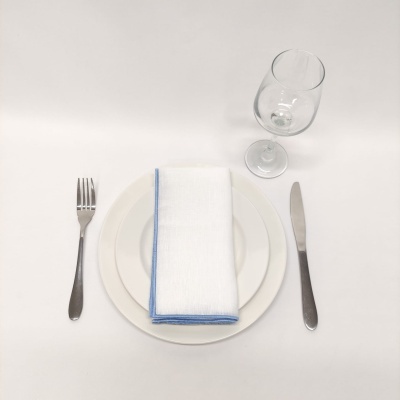 Conjunto de jantar com garfo, faca, dois pratos, guardanapo branco com borda azul e copo de vidro