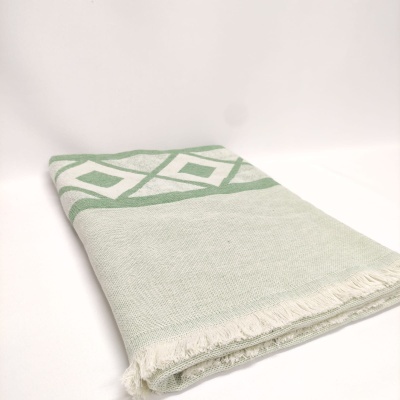 Toalha ou manta têxtil dobrada com padrão geométrico verde e branco