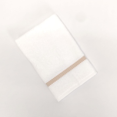 Toalha branca com faixa bege sobre fundo branco