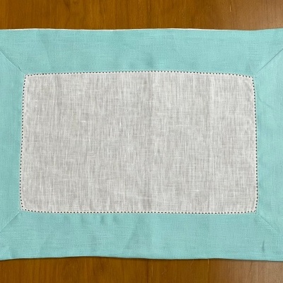 Toalha individual verde clara e cinzenta sobre superfície de madeira