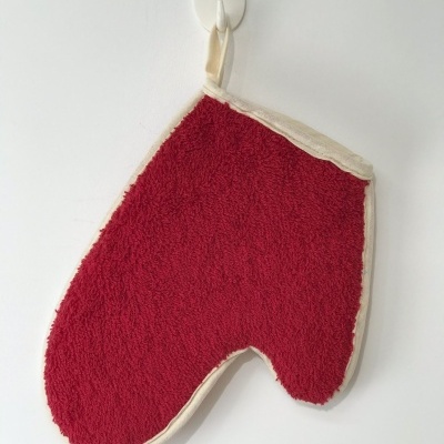 Luva de cozinha vermelha com bordas creme pendurada numa parede branca