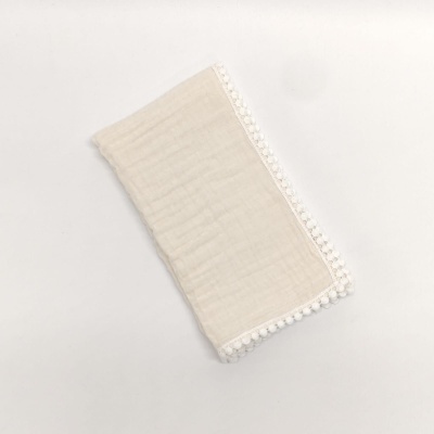 Guardanapo cru com borda de pompons brancos sobre fundo branco