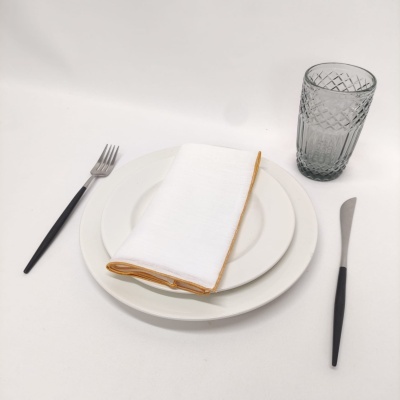 Conjunto de loiça branco com guardanapo, talheres pretos e copo cinza texturizado